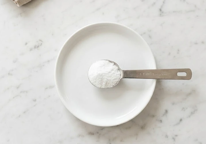 One level teaspoon of baking soda powder on white background showing portion size