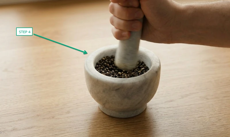 circular twisting motion of marble pestle grinding black peppercorns inside mortar